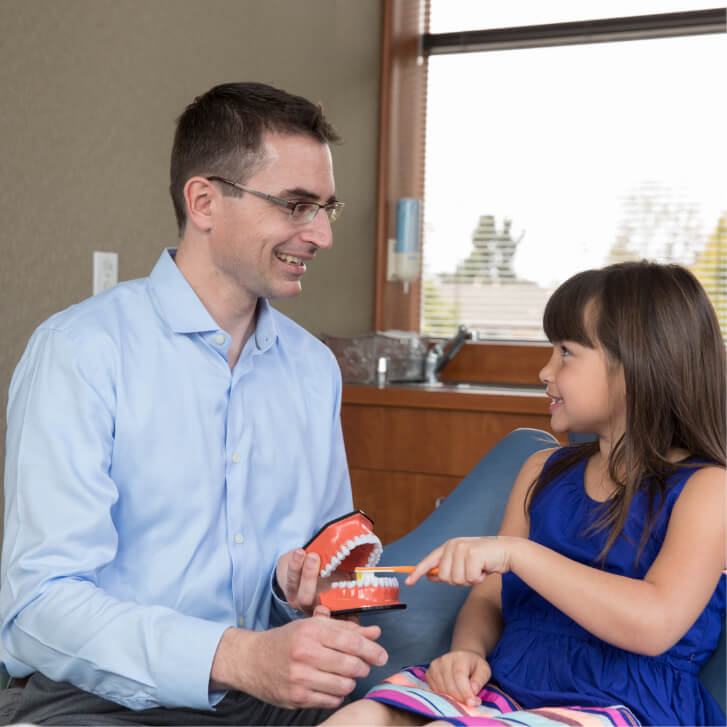 Dr. Fridgen showing a child how to brush teeth