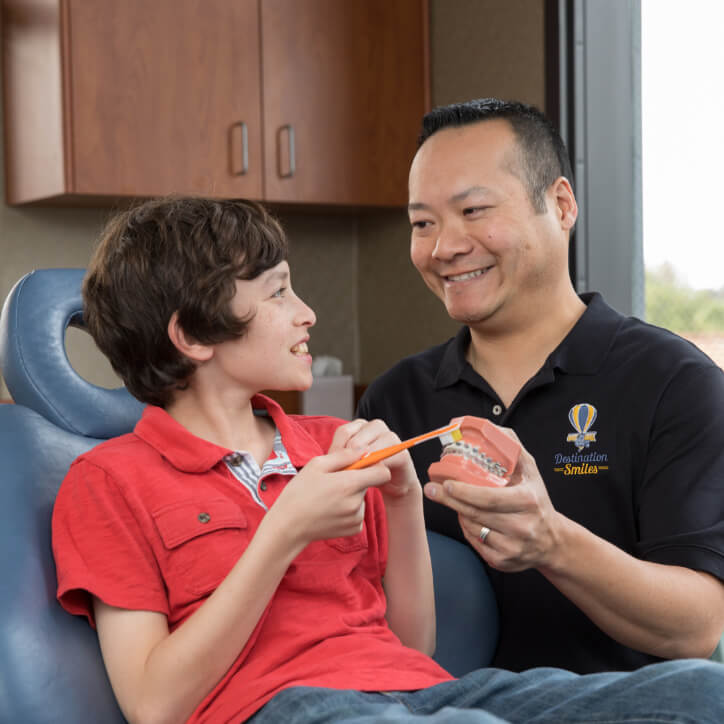 Dr. Kwong showing a child how to brush teeth